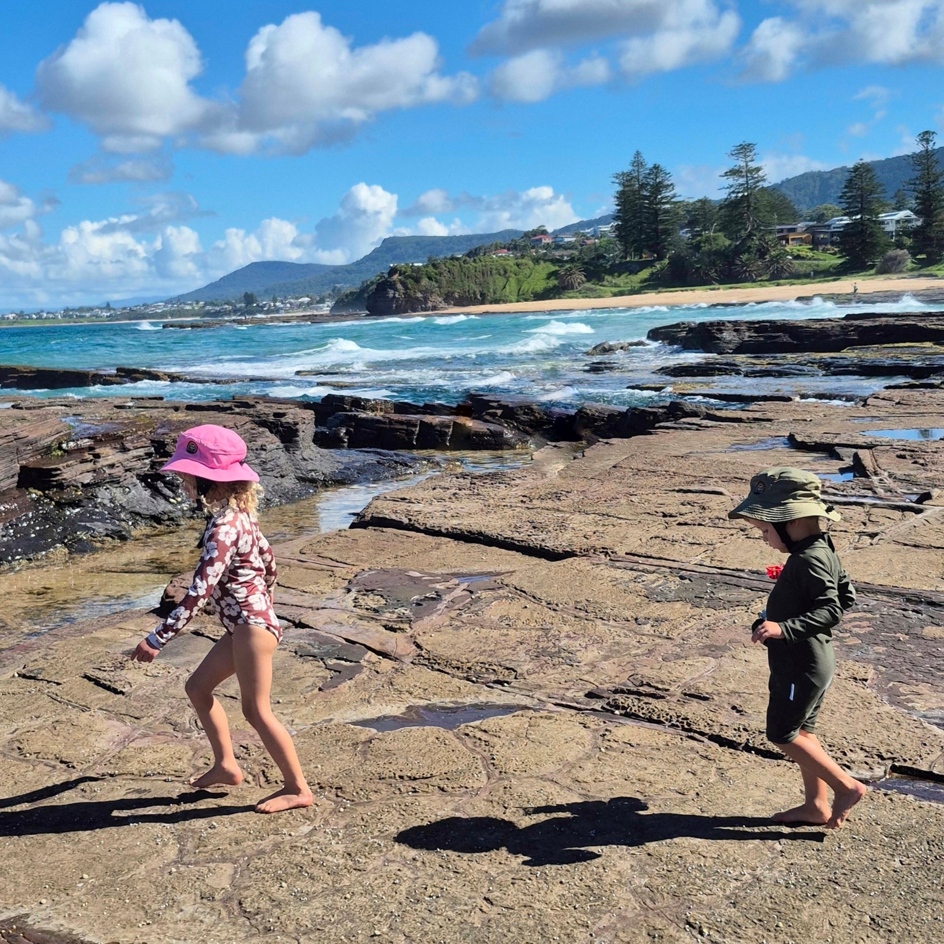 Kids walking on reef waring surf hats pink and green