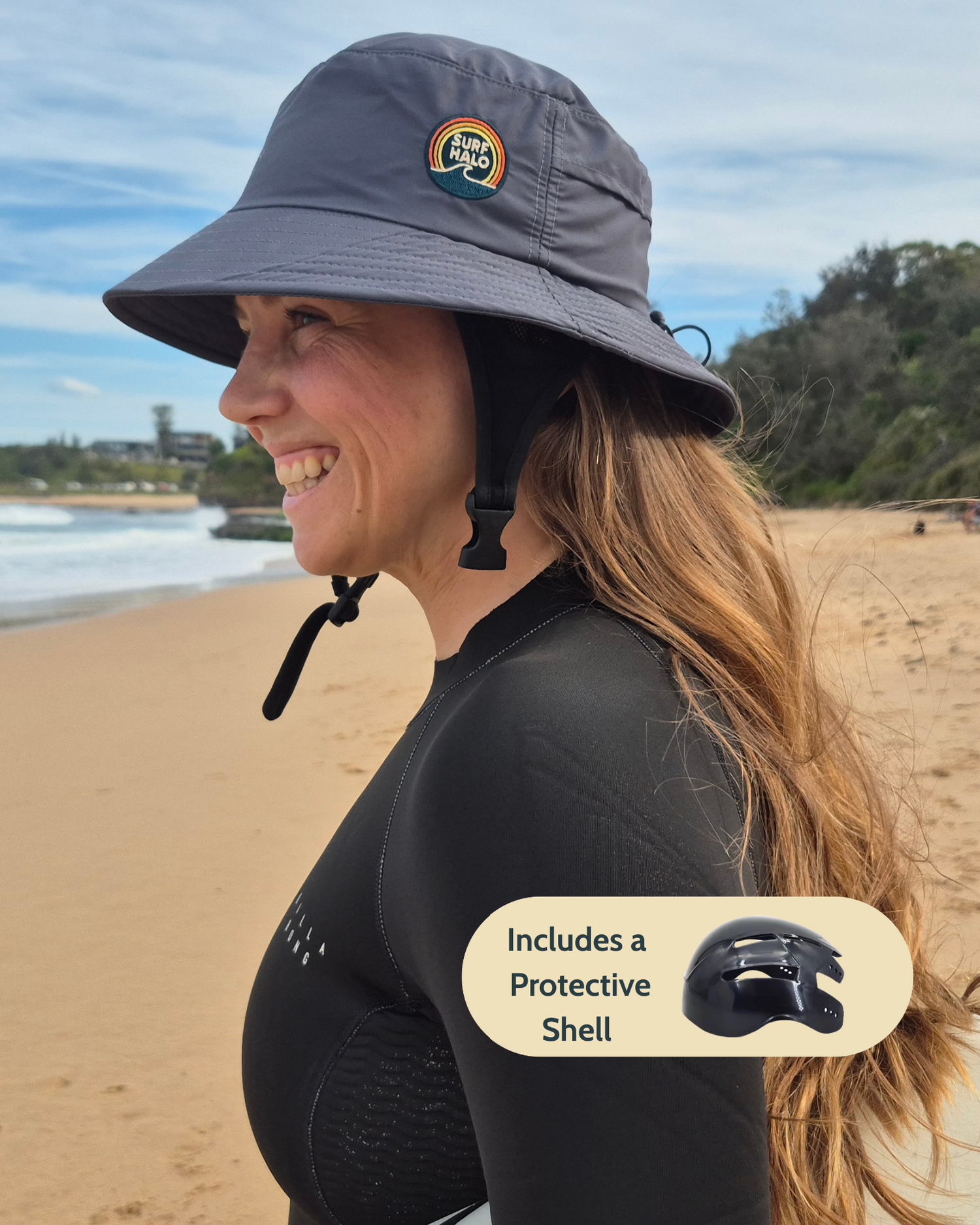 Woman on a beach wearing a protective helmet and sun hat with a rainbow logo.