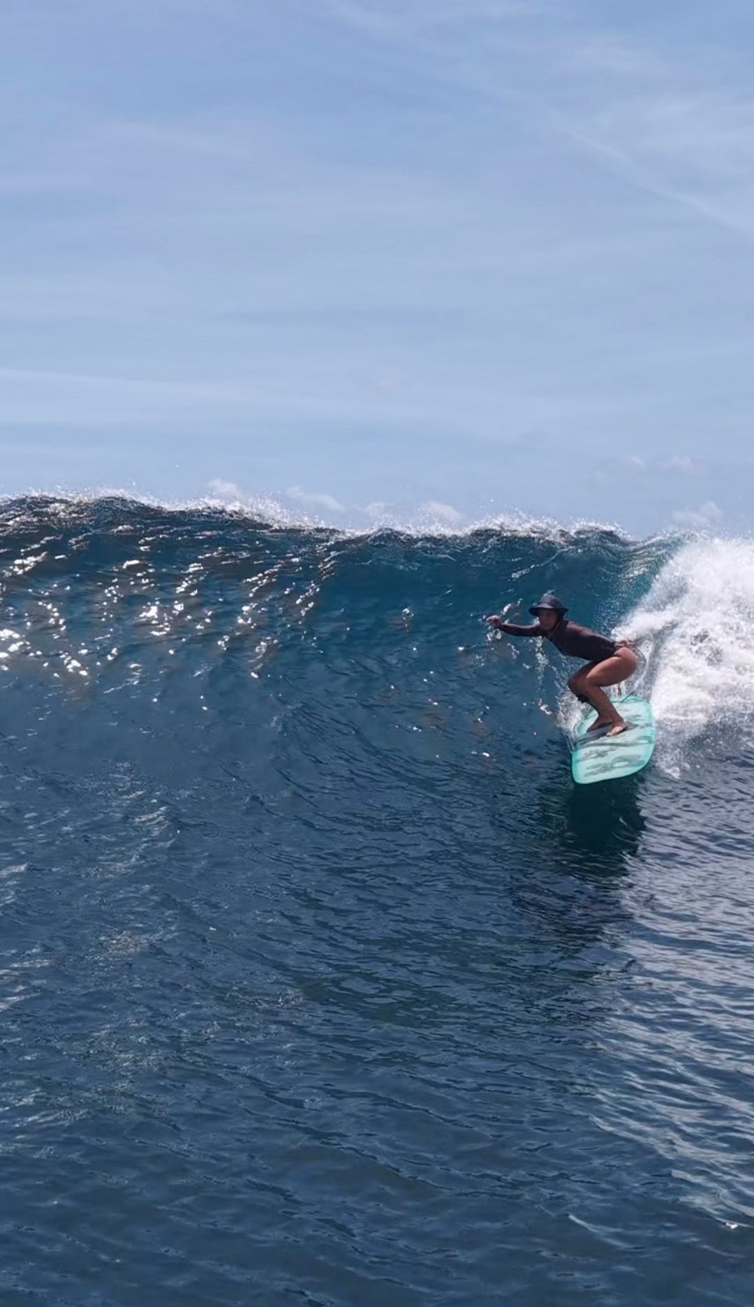 woman on a big longboard wave wearing a black bucket surf hat